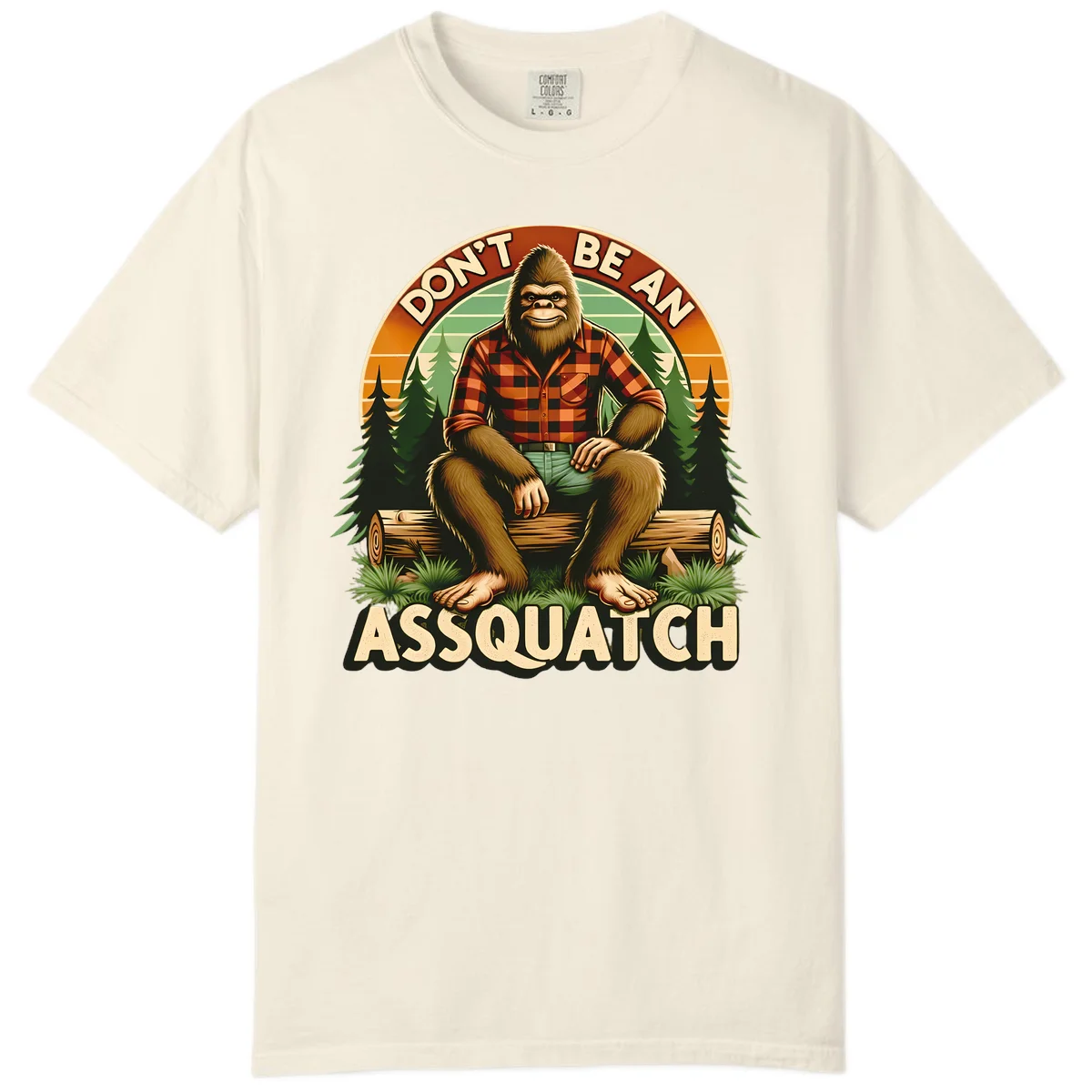 Vintage badge design with friendly Bigfoot in plaid shirt sitting on a log with forest trees, text reads 'Don't Be An Assquatch' in Ivory