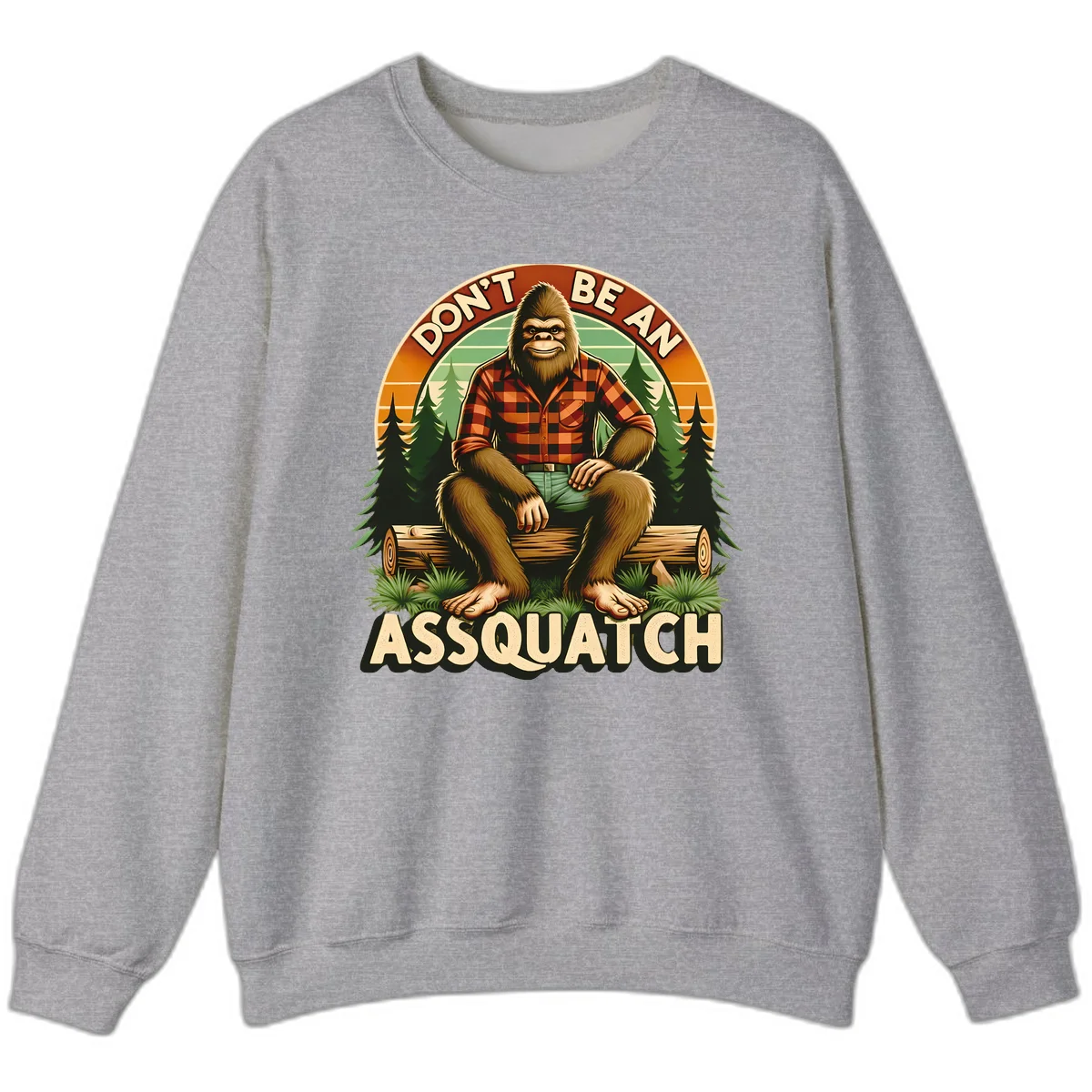 Vintage badge design with friendly Bigfoot in plaid shirt sitting on a log with forest trees, text reads 'Don't Be An Assquatch' in Sport Grey