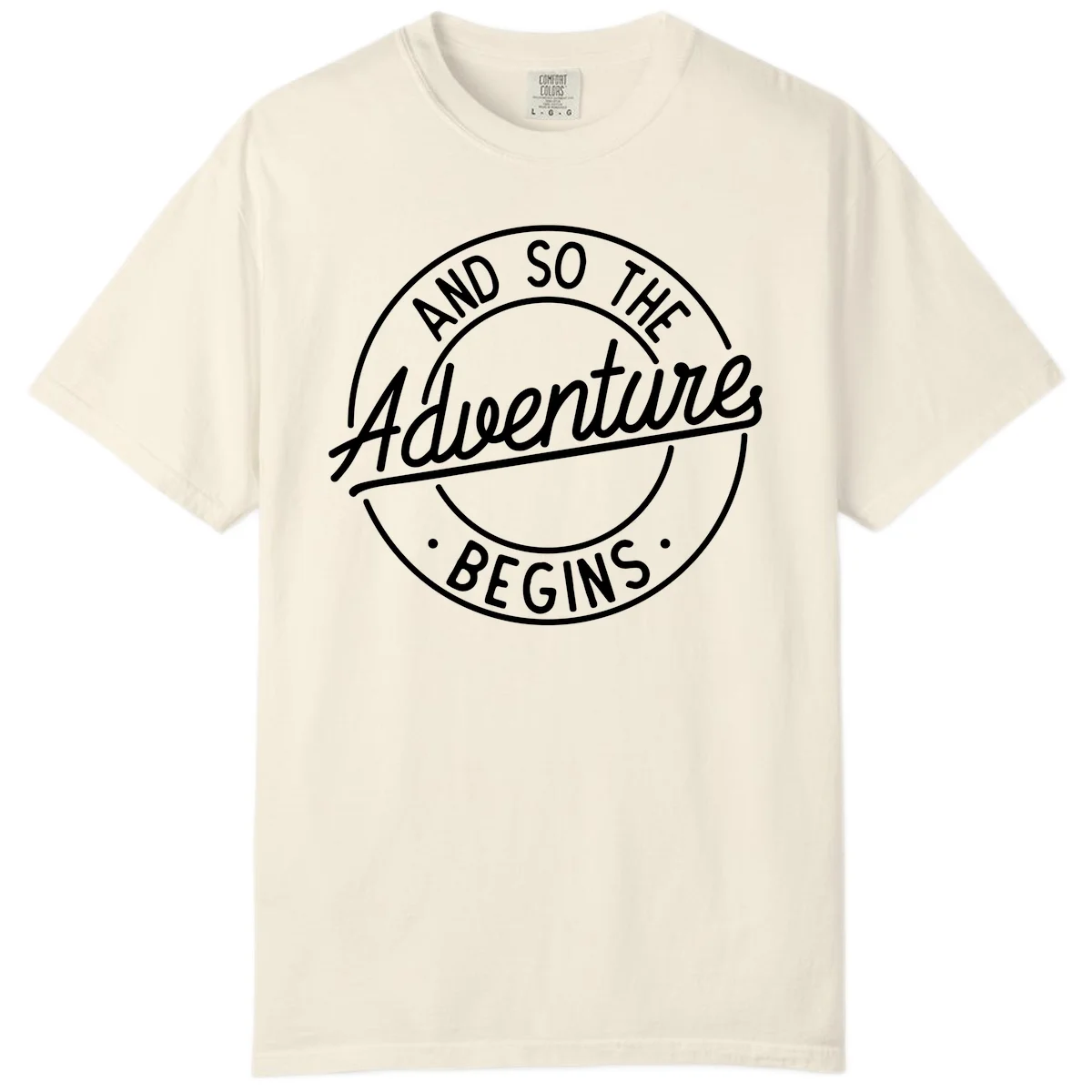 Vintage circular badge design with white text reading 'And So The Adventure Begins' on gray background in Ivory