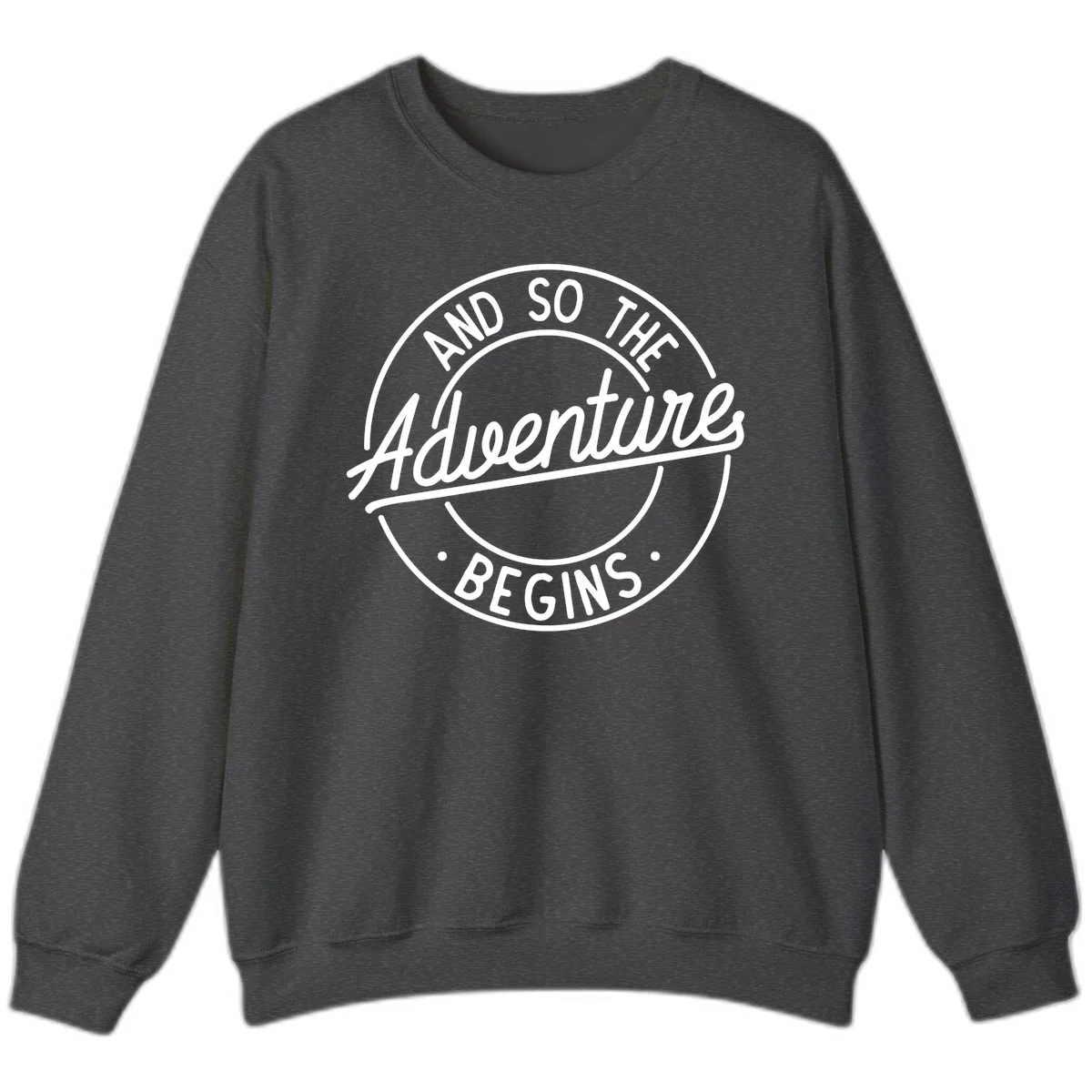Vintage circular badge design with white text reading 'And So The Adventure Begins' on gray background in Dark Heather